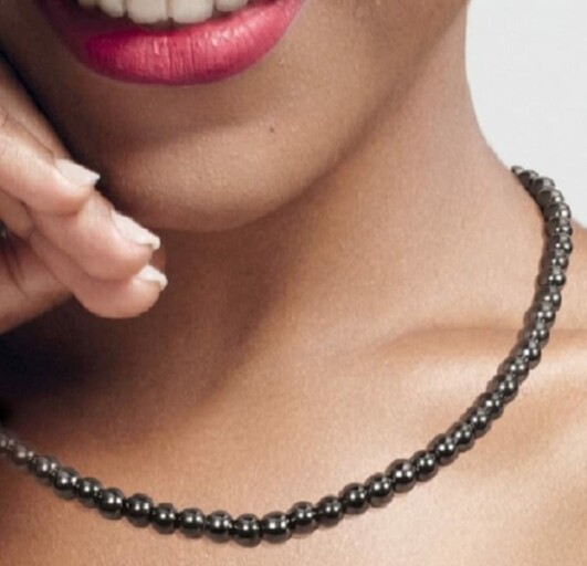 Kvinna med kort hår och halsband ler.