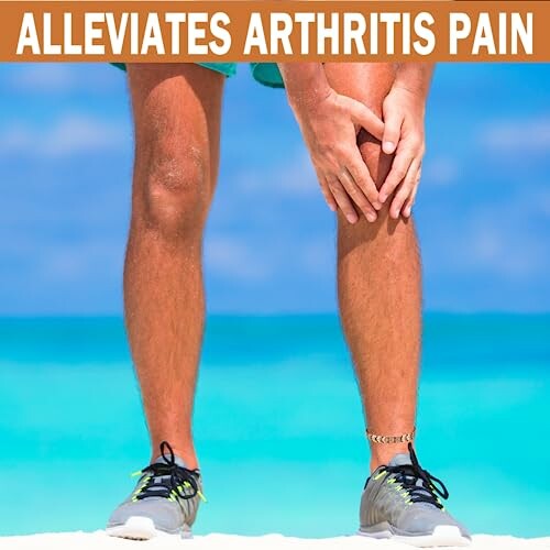 Person håller sitt knä på stranden mot artrit.