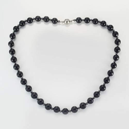 Svart pärlhalsband på vit bakgrund.