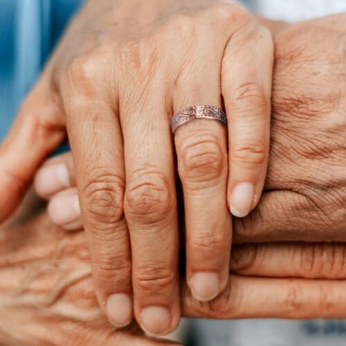 Närbild av händer som håller varandra med en ring på fingret.