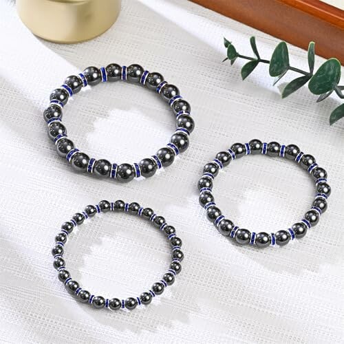 Tre magnetiska pärlarmband på vit bakgrund.