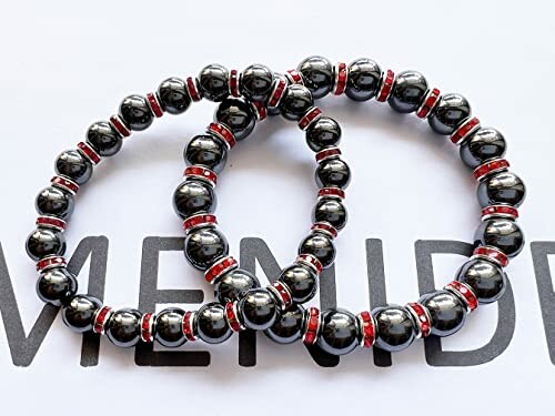 Två magnetiska hematitarmband med röda detaljer.