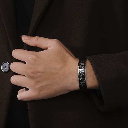 Hand med svart armband med runor