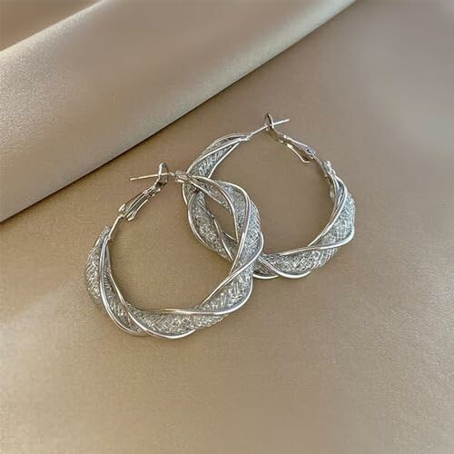 Silvriga örhängen i spiralform på tyg.